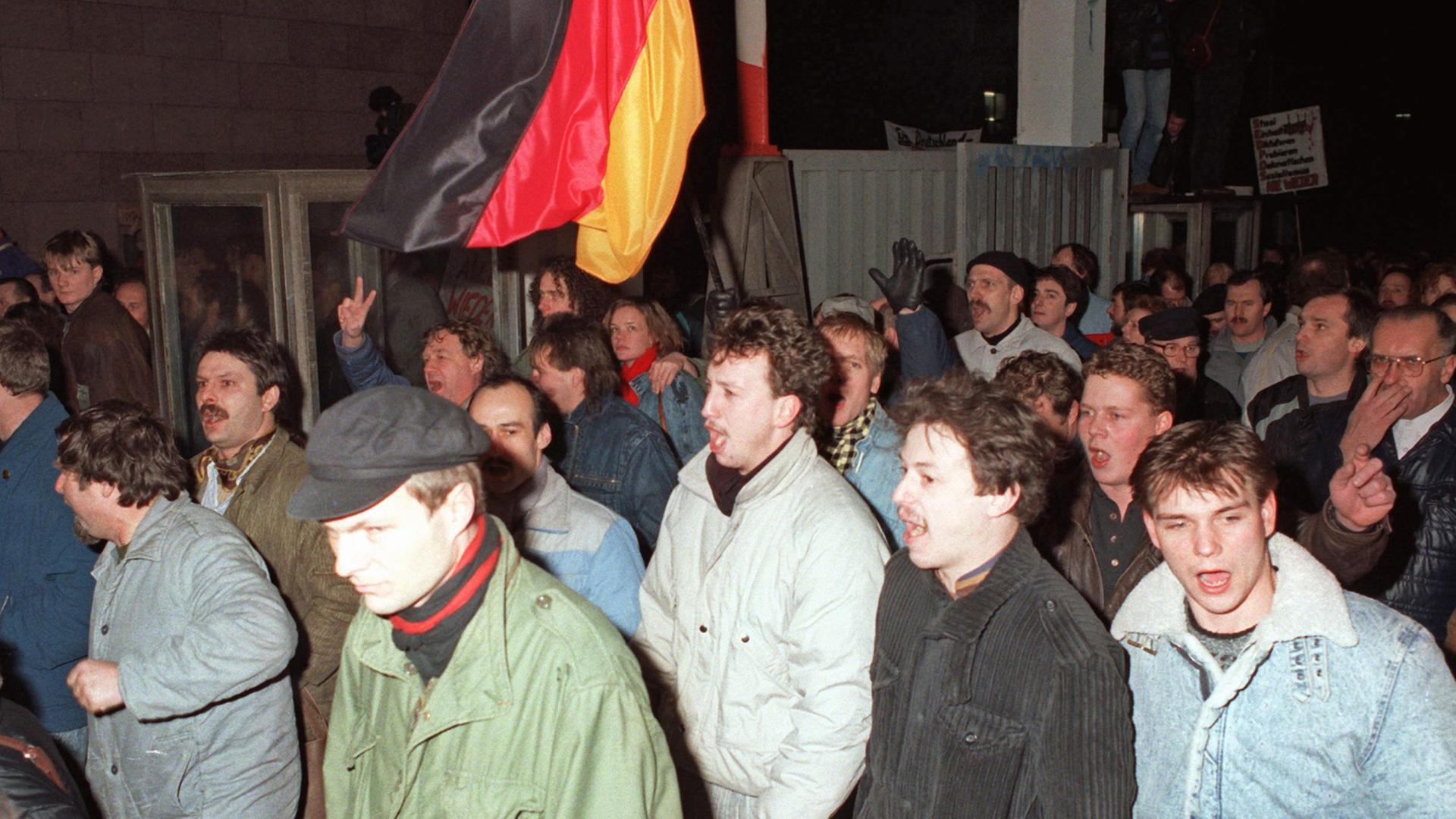 Eine große Menschenmenge im Dunkeln vor der Zentrale; jemand schwenkt eine Deutschland-Fahne