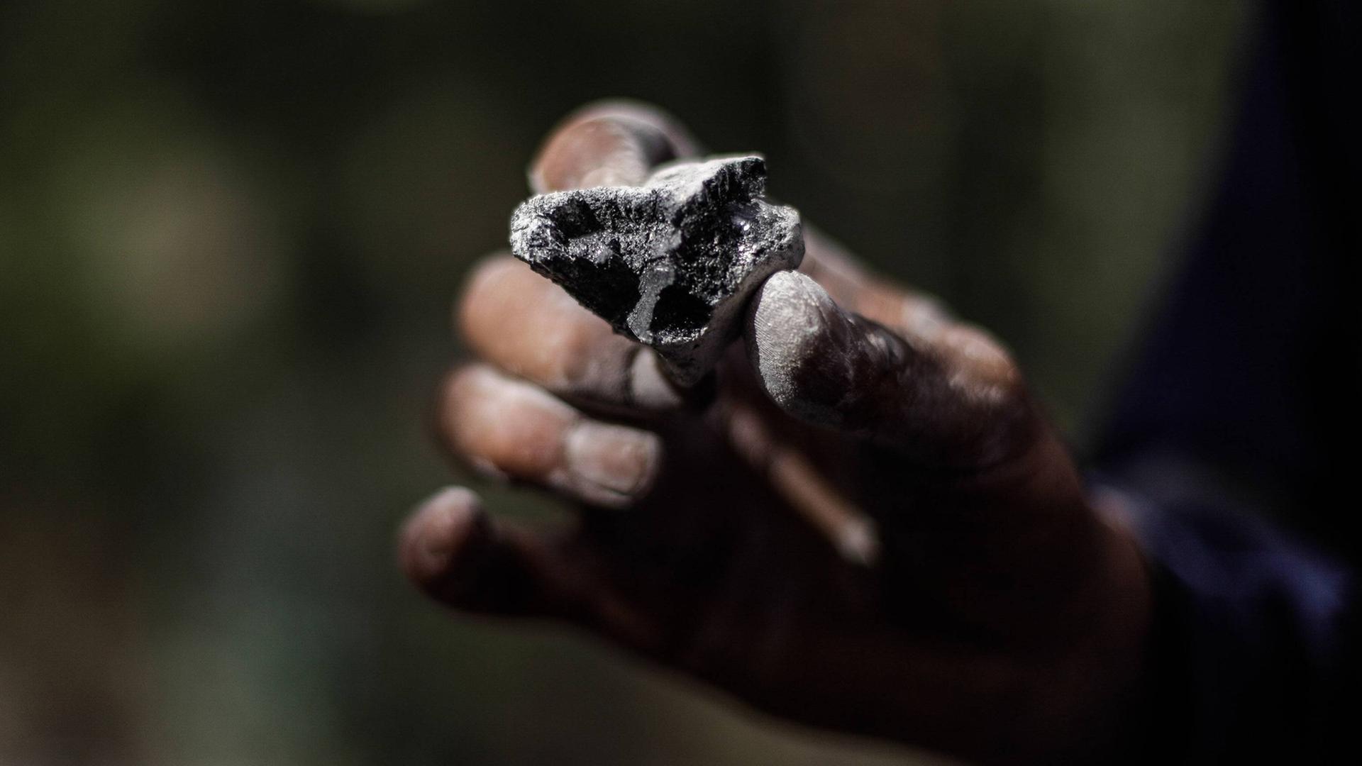 Eine Hand hält ein Stückchen Kohle. Symbol einer endenden Energie-Ära