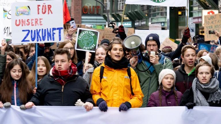 Fridays for Future: Die schwedische Aktivistin Thunberg beim Klimaprotest in Hamburg. Zahlreiche Demonstrantinnen und Demonstranten gehen durch die Straßen und halten ein Transparent vor sich.