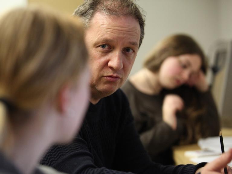 Der Autor Manfred Theisen im Gespräch mit Schülerinnen während einer lyrix-Schreibwerkstatt zum Thema "Krieg und Frieden" im NS-Dokumentattionszentrum in Köln.