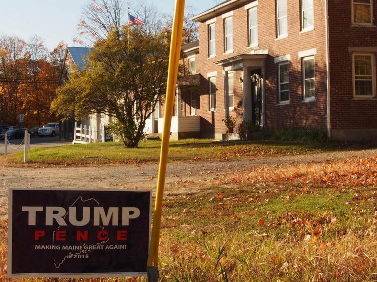 Eine Wohnsiedlung im US-Ostküstenstaat Maine im Herbst. Im Vordergrund ein Wahlplakat für Donald Trump.