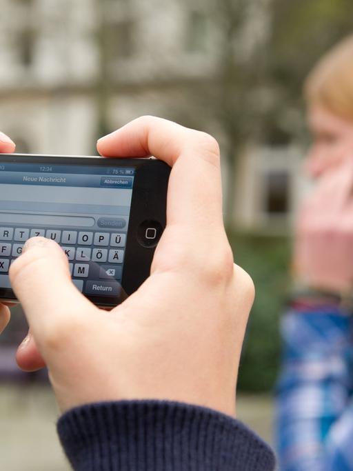Schüler schreiben SMS und telefonieren am 22.04.2013 auf einem Schulhof in Braunschweig (Niedersachsen).
