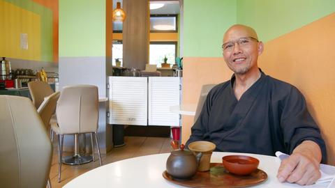 Nguyen Thanh Hieu sitzt in seinem Restaurant an einem Tisch und blickt freundlich in die Kamera