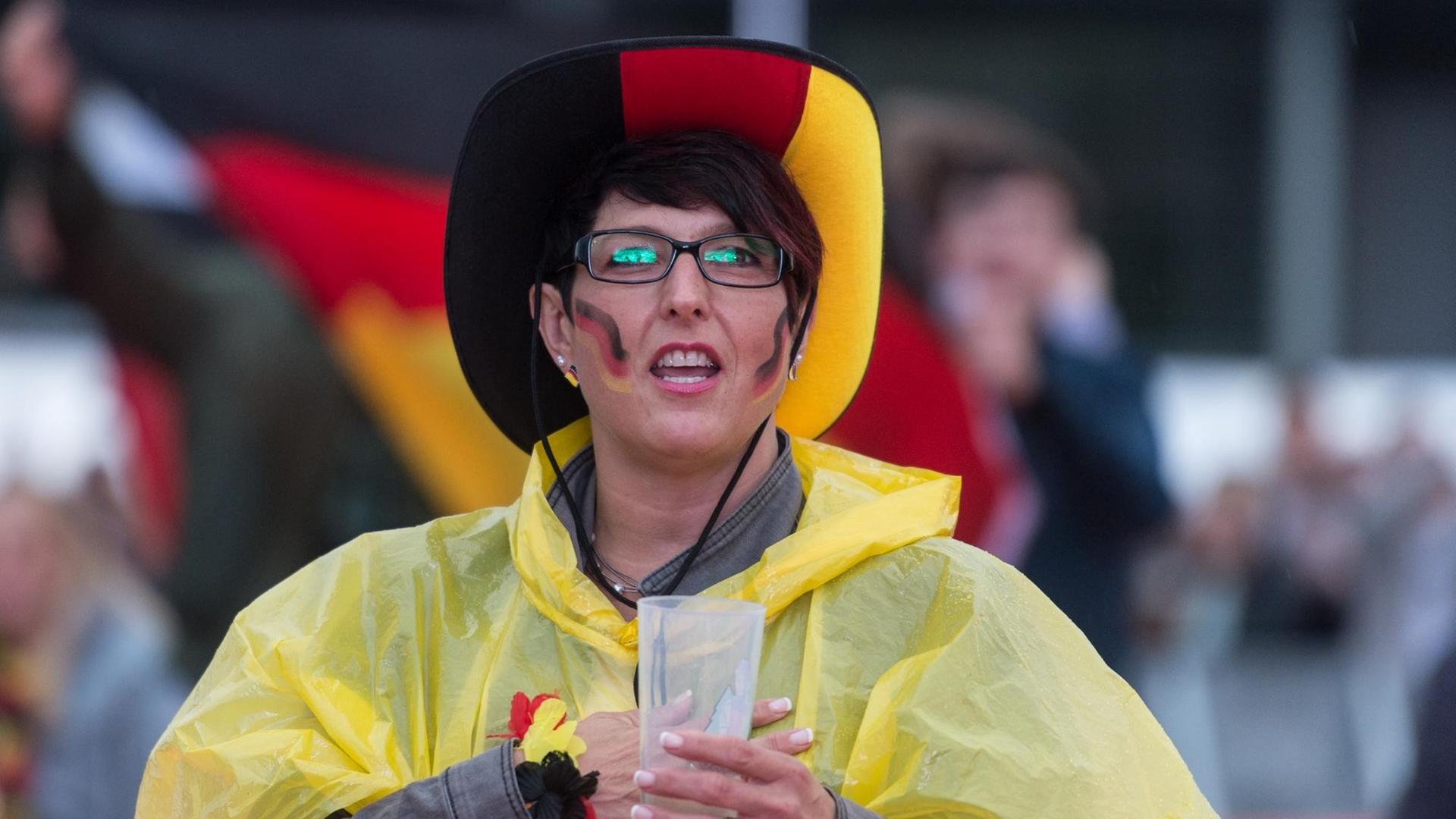 Ein deutscher Fußball-Fan singt am 16.06.2016 beim Public Viewing auf dem Messegelände in Freiburg (Baden-Württemberg) im Regen vor der EM-Begegnung Deutschland - Polen die deutsche Nationalhymne.