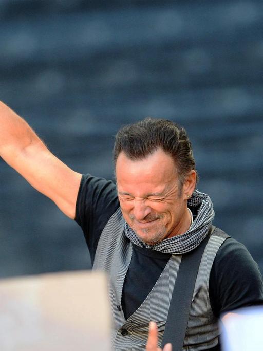 Der US-Rockstar Bruce Springsteen steht auf einer Bühne mit gesclossenen Augen und hält ein Mikrofon Richtung Publikum