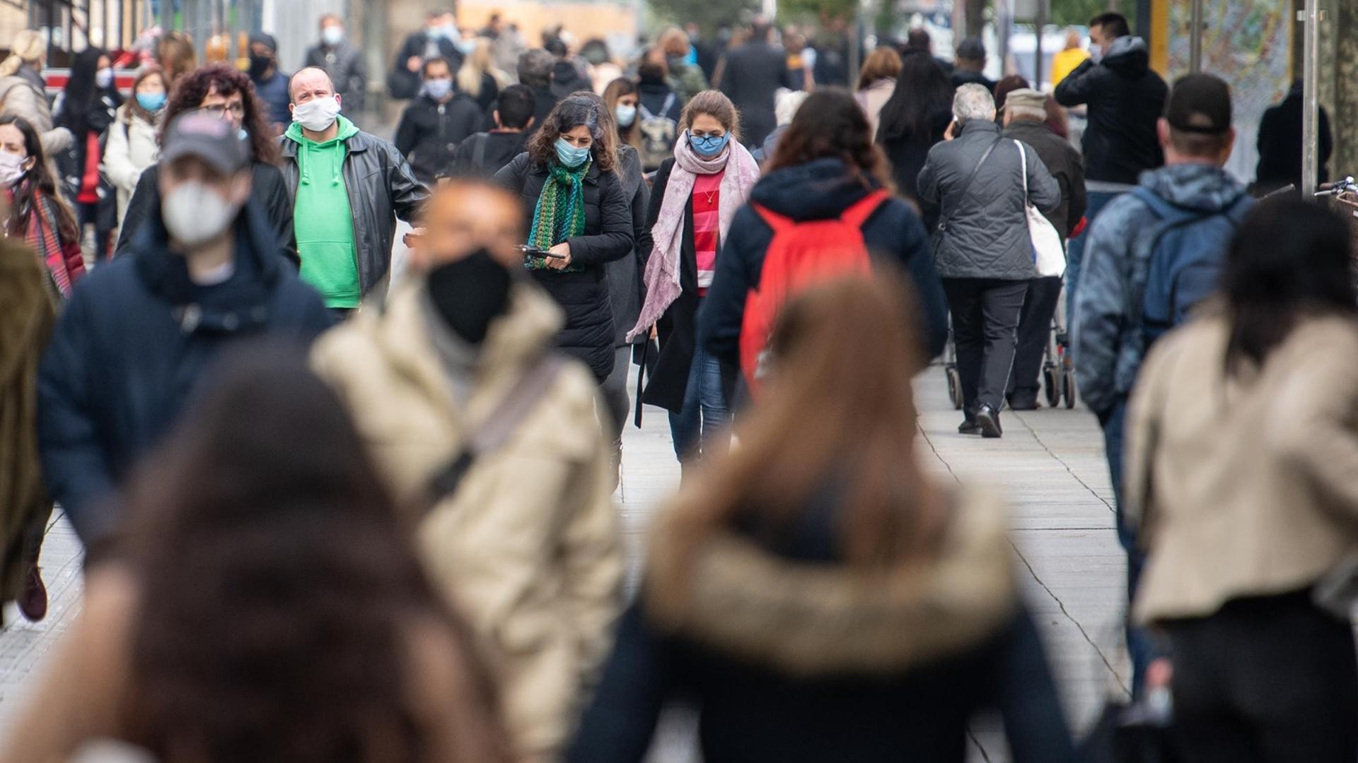 Passanten tragen Mund-Nasenschutz, während sie durch die Stuttgarter Innenstadt gehen.