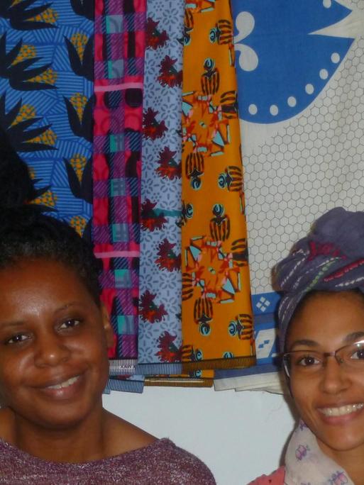 Die Designerinnen Wacy Zacarias (l.) und Djamila Machava de Sousa aus Mosambik vor ihren Capulanas - den bunt bedruckten Stoffen aus Mosambik