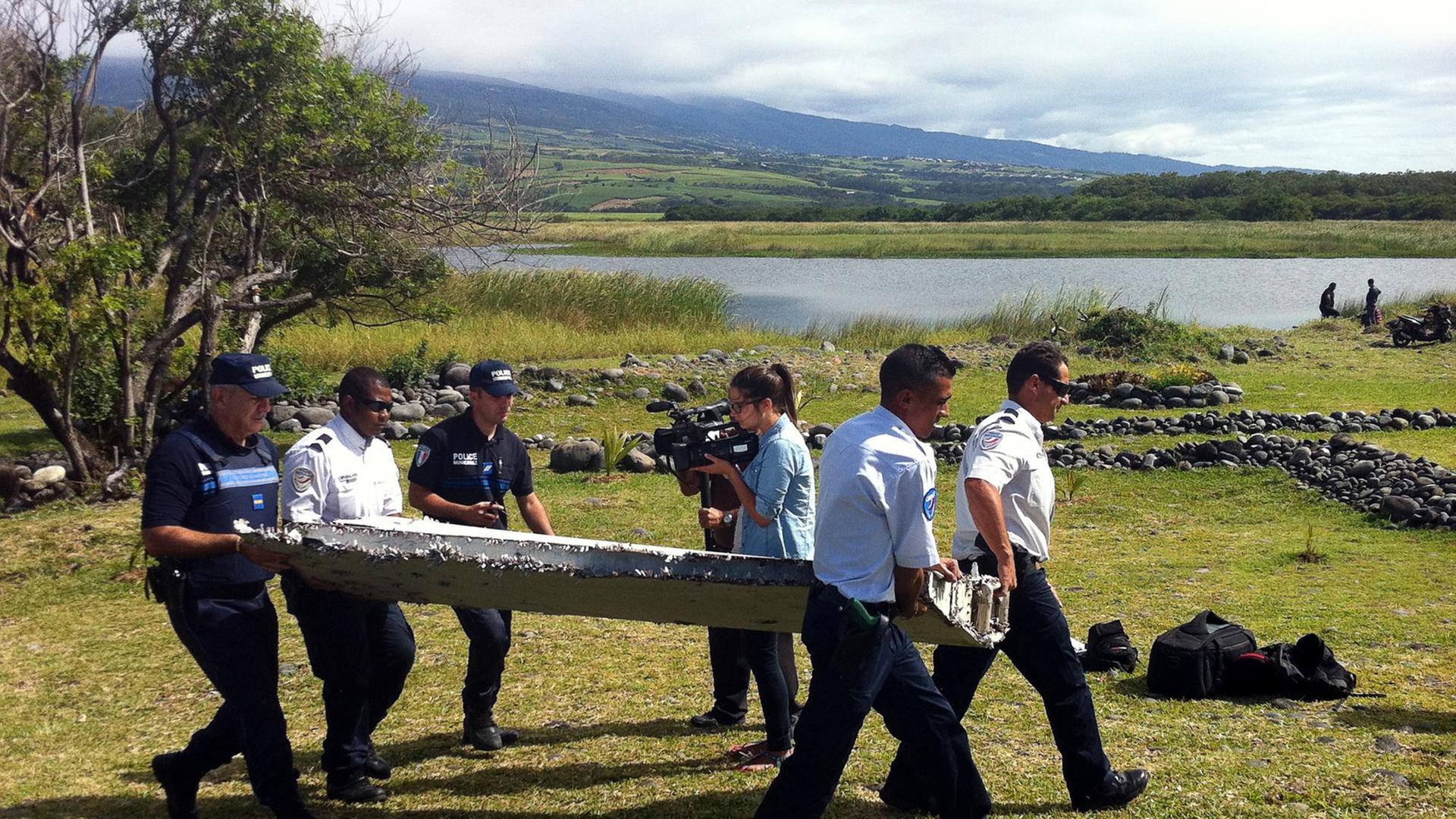 Nach mehr als einem Jahr eine erste Spur von Flug MH370? Polizisten mit dem auf der Insel La Réunion gefundenen Wrackteil.