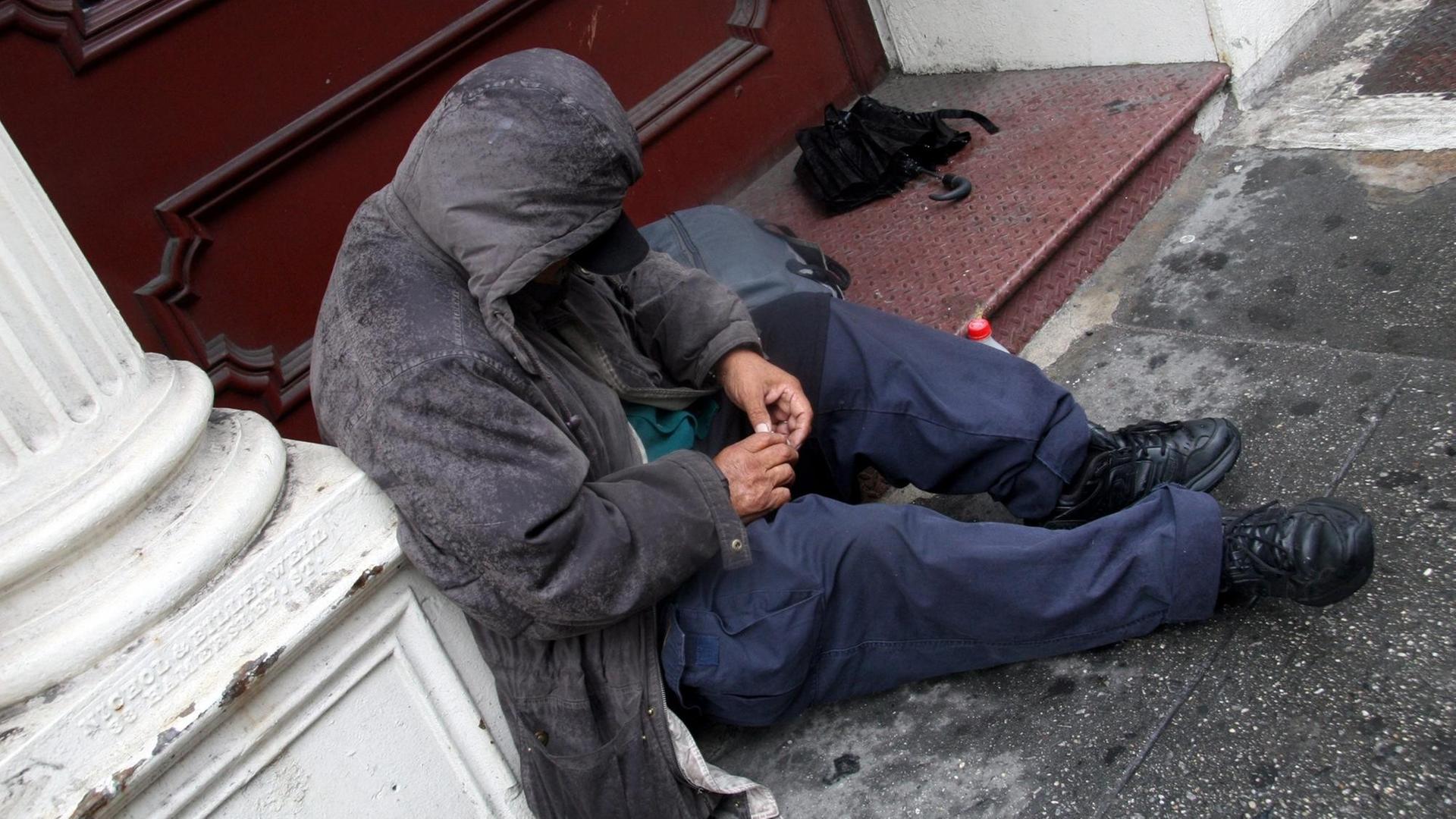 Ein Obdachloser sitzt im Hauseingang einer Straße in der US-Metropole New York.