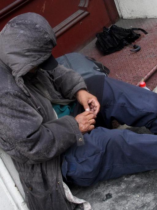 Ein Obdachloser sitzt im Hauseingang einer Straße in der US-Metropole New York.