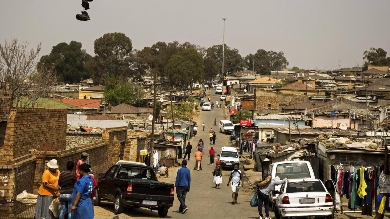 Außenaufnahme der Stadt Alexandra, Blick auf den Ortseingang mit Häusern, Autos und Menschen.