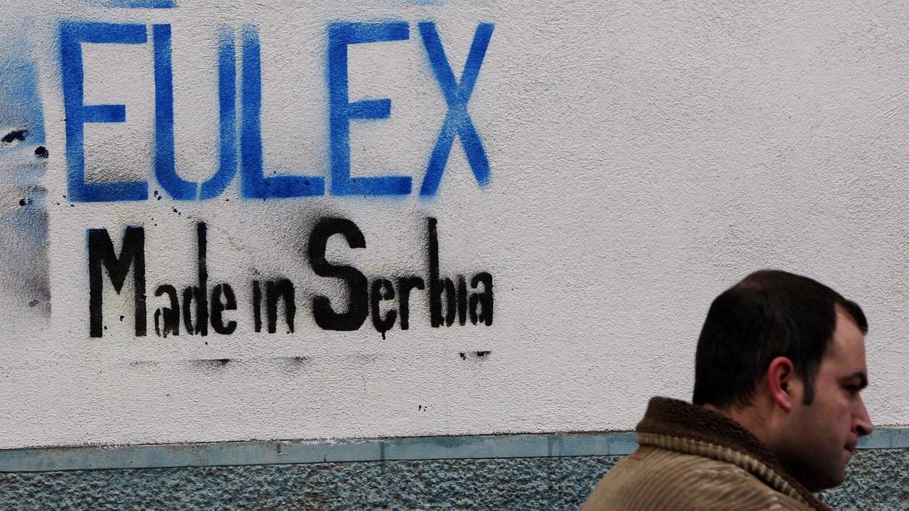 Ein kosovo-albanischer Mann geht am 28. November 2008 in Pristina, Kosovo, vorbei an einem Graffiti mit der Aufschrift "EULEX Made in Serbia". 