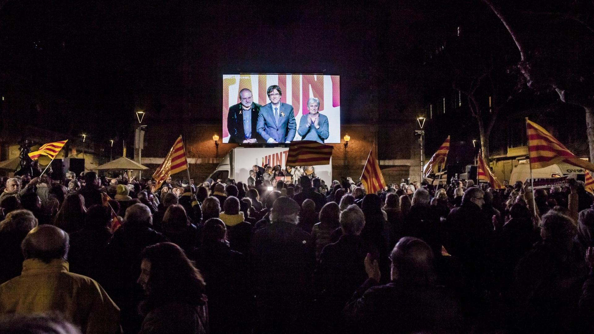 Der abgesetzte katalanische Regierungschef Carles Puigdemont ist auf einer Leinwand auf einer Kundgebung in Barcelona zu sehen. Er wurde zugeschaltet aus Brüssel, wseil in Spanien noch ein Haftbefehl gegen ihn vorliegt.