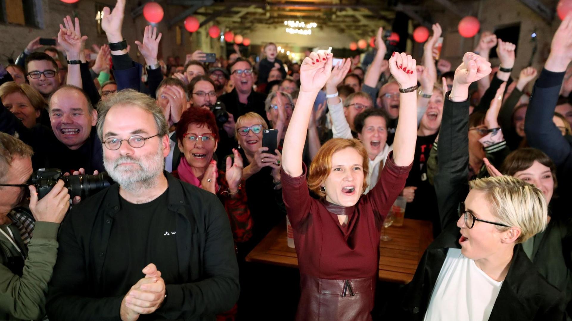 Unterstützer der Linken reagieren auf die ersten Prognosen zum Ergebnis der Landtagswahl in Thüringen mit Jubel und hochgereckten Armen.