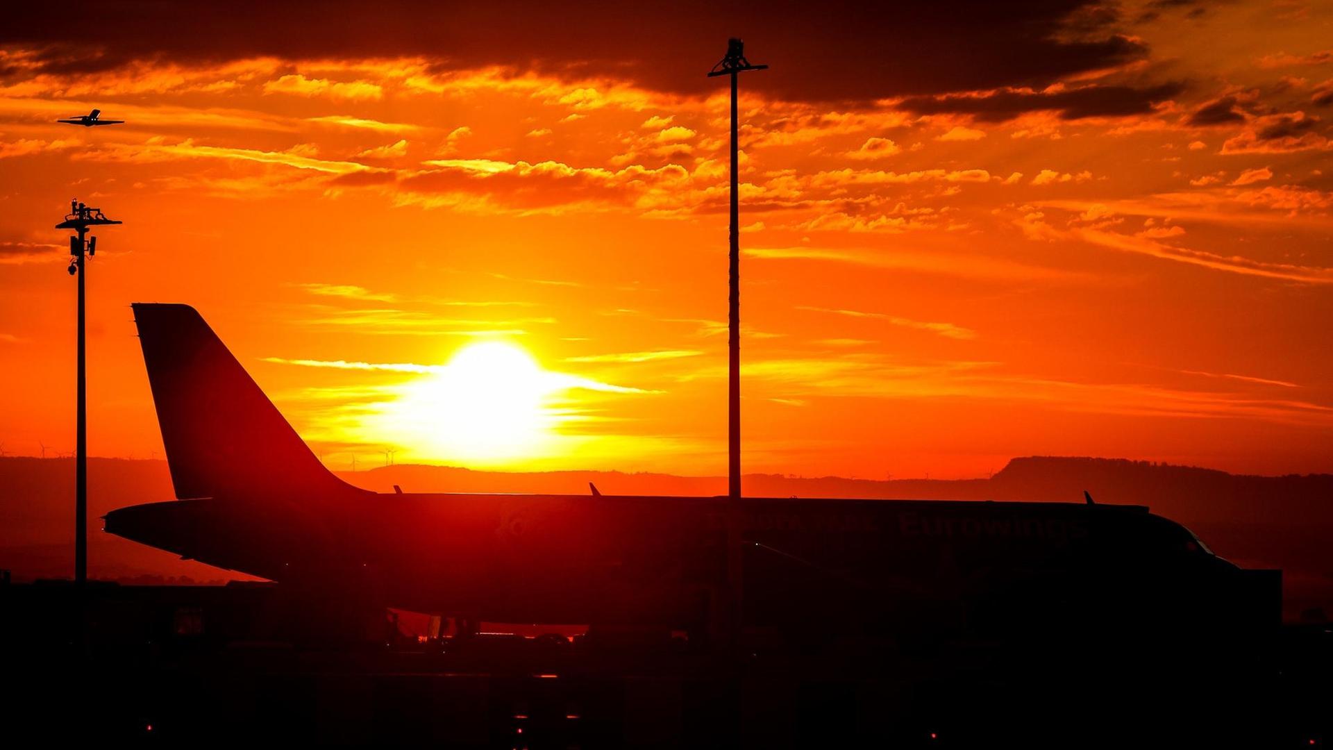 Die Sonne geht über einem Airbus am Flughafen auf.