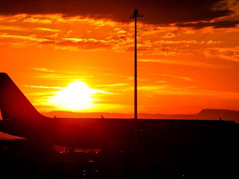 Die Sonne geht über einem Airbus am Flughafen auf.