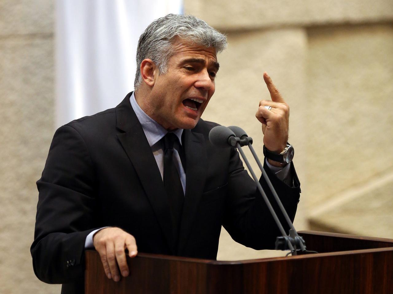 Israels Finanzminister Yair Lapid (Partei Yesh Atid) sprechend und gestikulierend an einem Rednerpult.