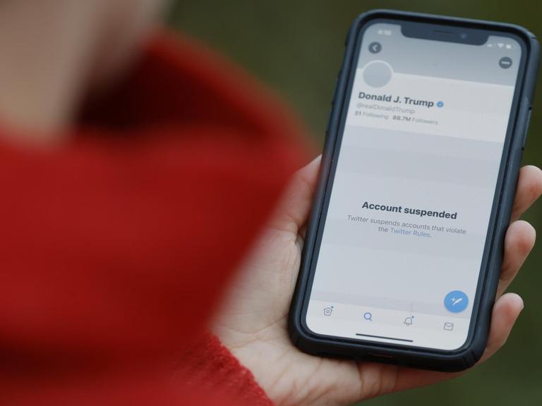 Person hält ein Smartphone in der Hand, das den suspendierten Twitter-Account von Donald Trump zeigt.