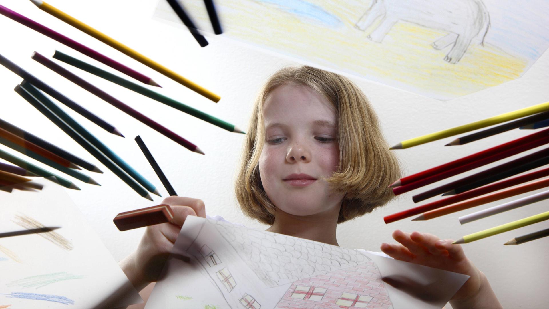 Ein 11-jähriges Mädchen malt mit Buntstiften ein Bild.