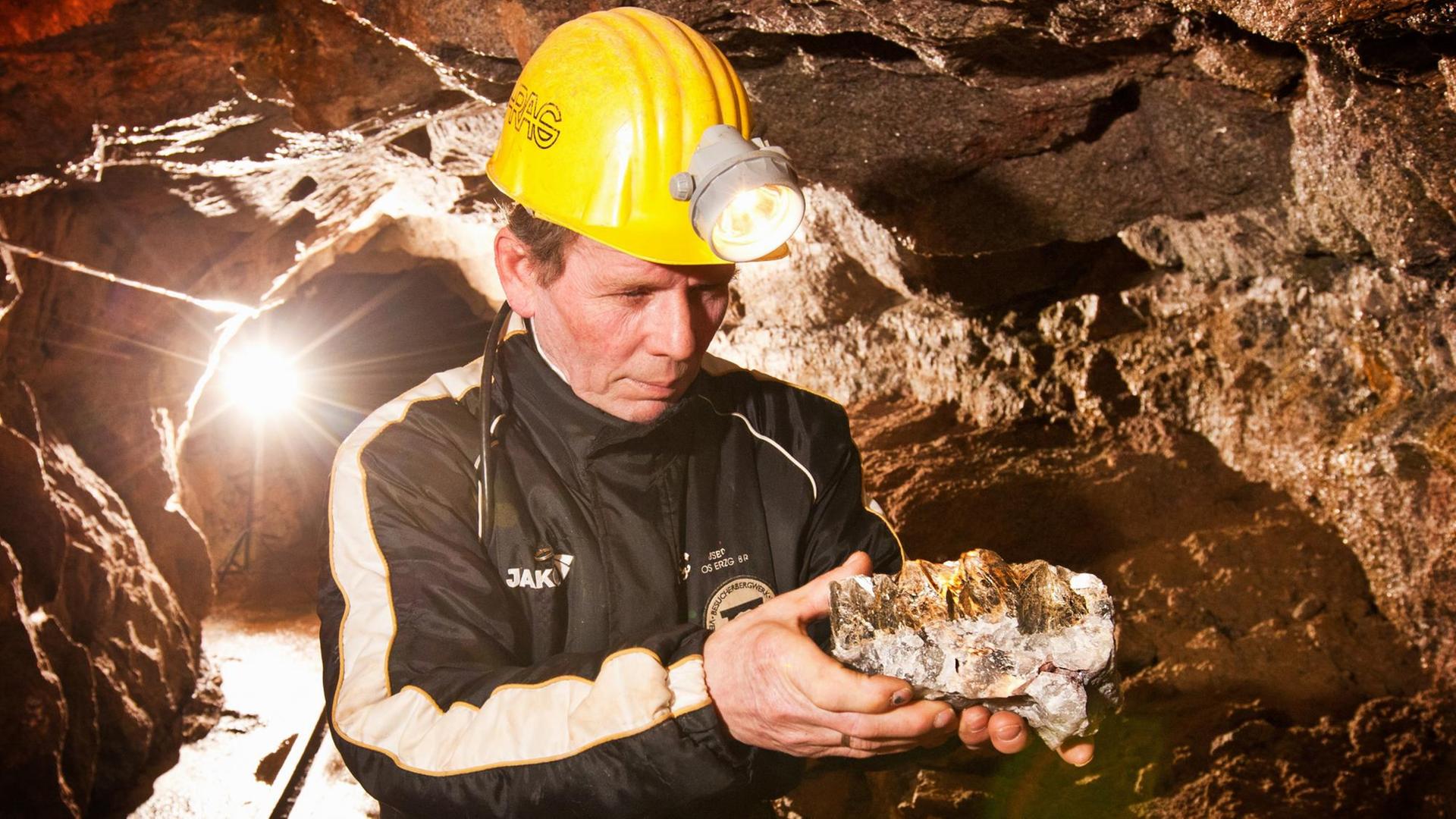 Ein Bergmann zeigt im einem Bergwerk im Erzgebirge einen Gesteinsbrocken mit Lithium.