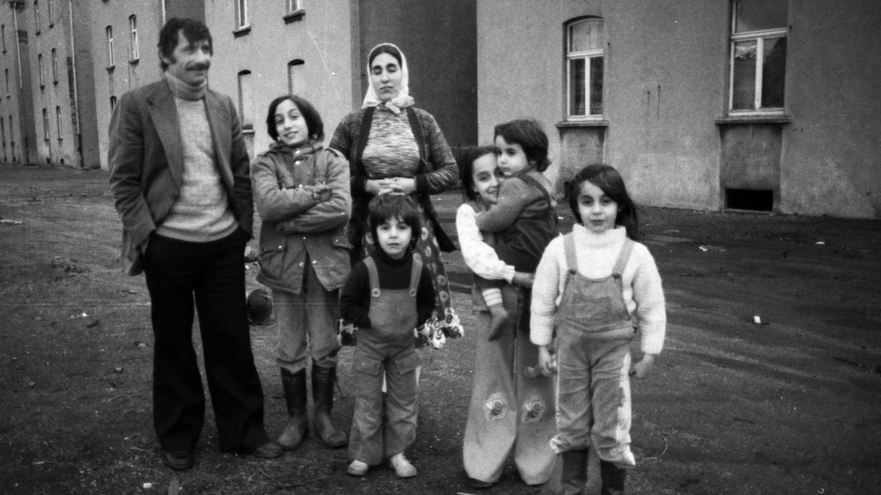 Das Schwarz-Weiß-Foto zeigt eine türkische Familie vor einem Häuserblock. Das Schwarz-Weiß-Foto zeigt eine türkische Familie vor einem Häuserblock.