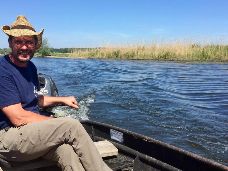 Der Fischer Wolfgang Schröder mit Sonnenhut in seinem Boot auf der Havel