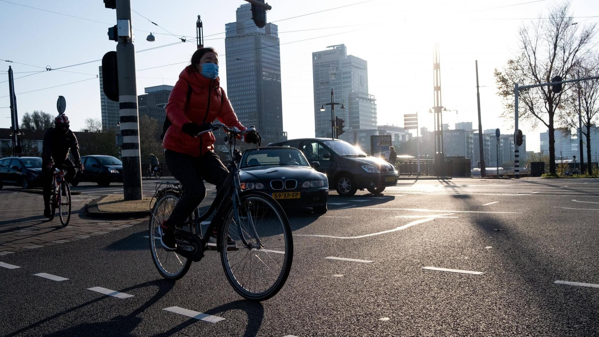 Eine Radfahrerin fährt mit Mund-Nasen-Bedeckung durch Amsterdam