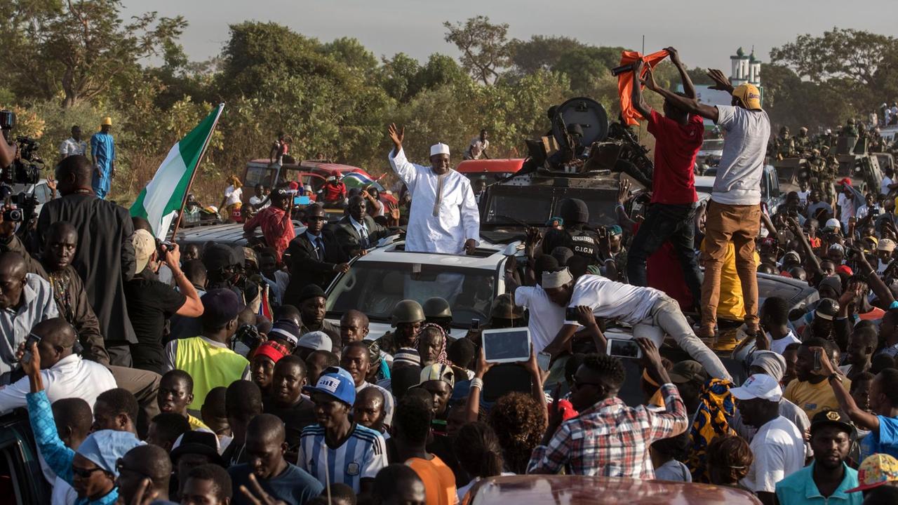 Adama Barrow fährt durch die ihn begrüßende Menschenmenge und schaut dabei aus dem Dachfenster seines Autos.