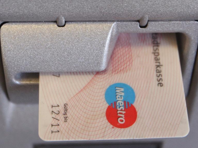 Eine EC-Karte steckt im Schlitz eines Geldautomaten