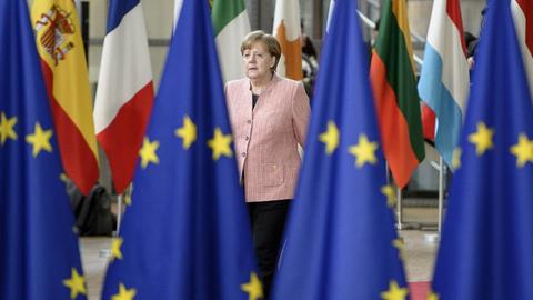 Angela Merkel geht am 22.03.2017 im Europäischen Rat einen mit Flaggen gesäumten Weg entlang. Im Vordergrund sind vier Europaflaggen zu sehen.