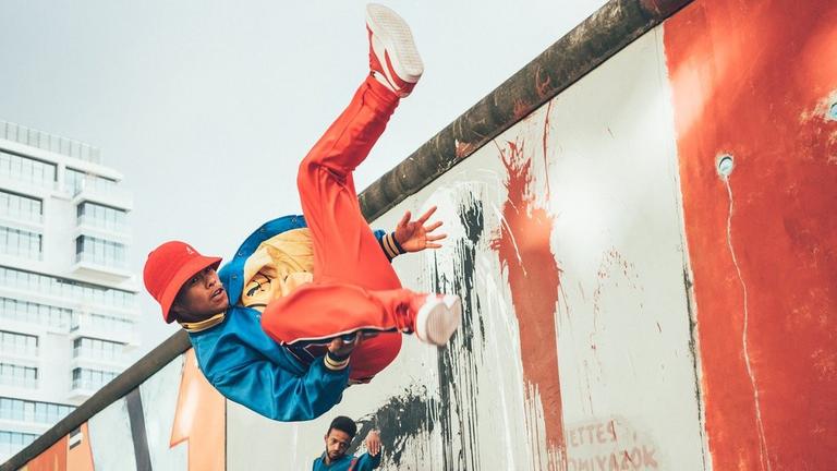 Ein Breakdancer von "Flying Steps" tanzt vor einer Wand mit Graffitis.