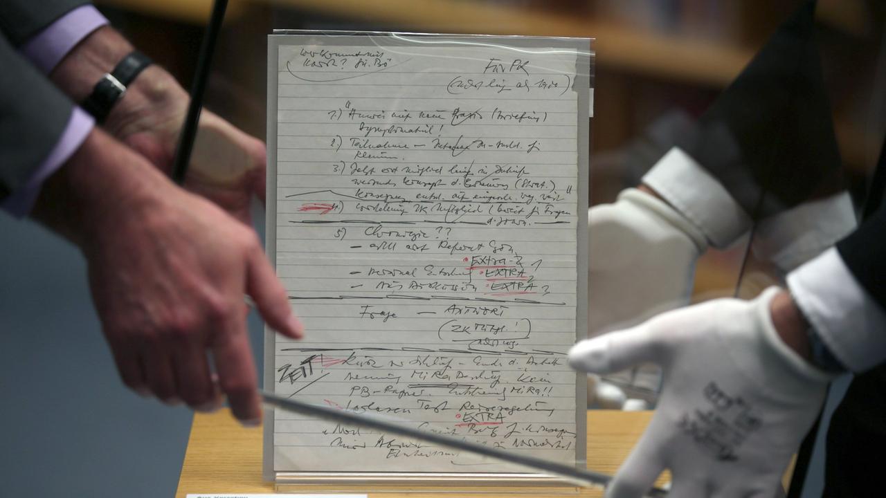 Mitarbeiter stülpen im Haus der Geschichte eine Glasvitrine über den Schabowski-Zettel.