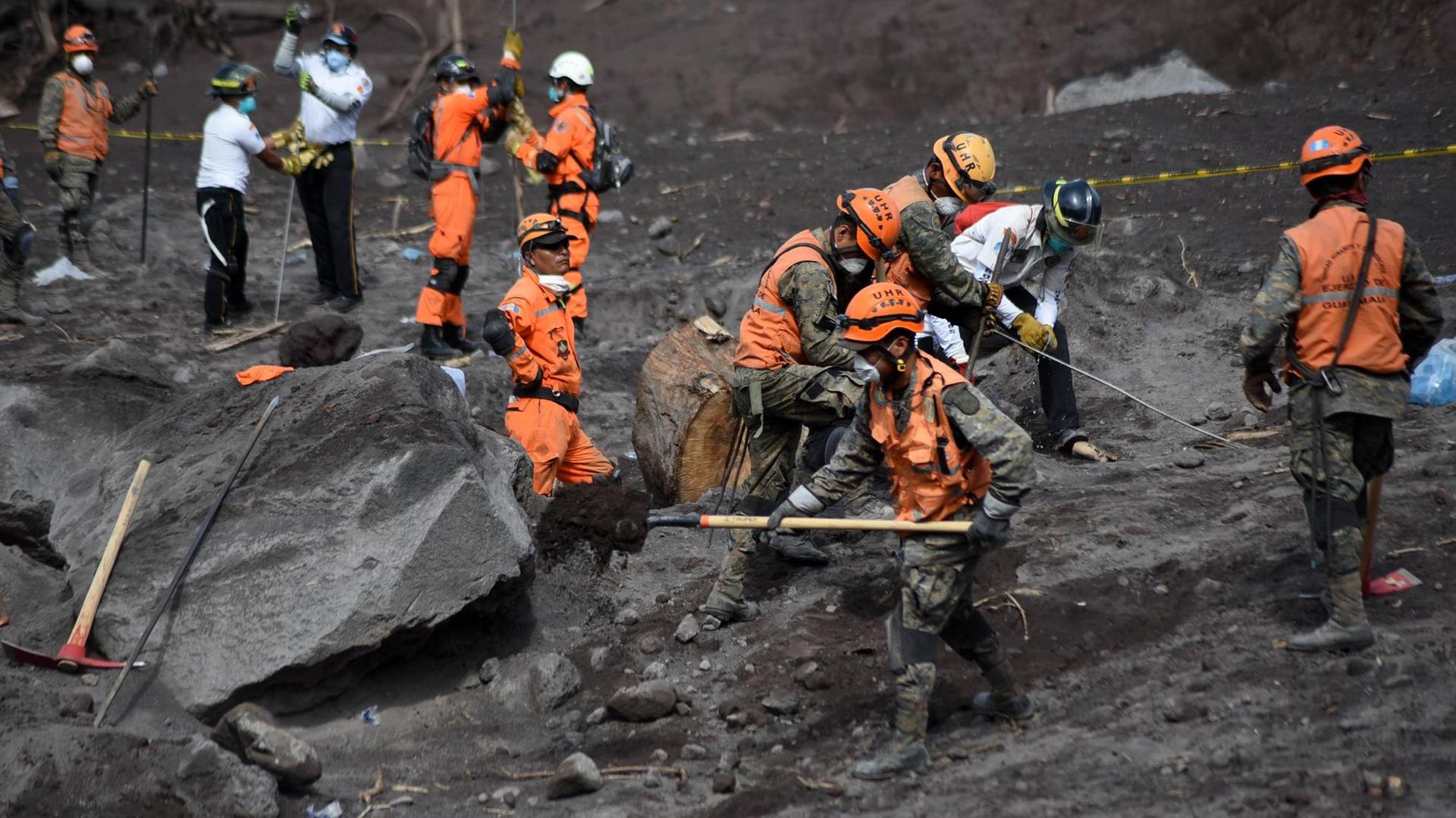  Freiwillige und Feuerwehr-Leute suchen in der Asche nach Überlebenden und Opfern.