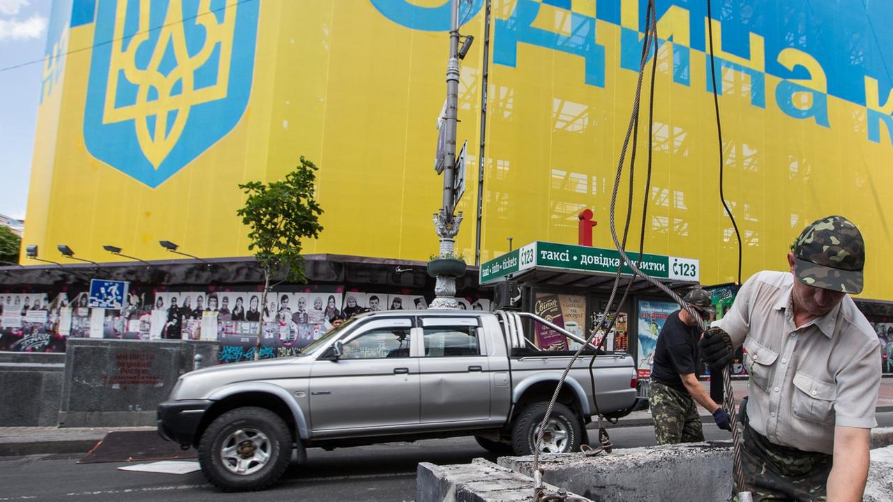 Bauarbeiter demontieren eine Straßenbarrikade der Majdan-Aktivisten in Kiew.