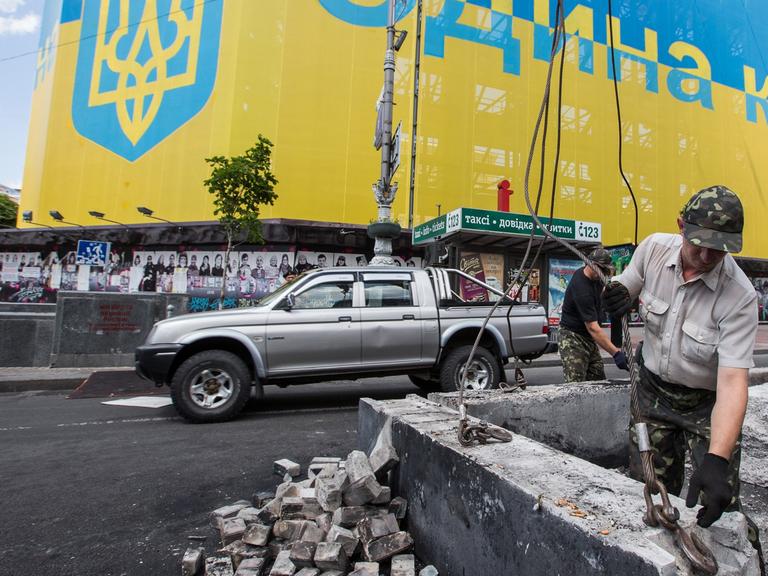 Bauarbeiter demontieren eine Straßenbarrikade der Majdan-Aktivisten in Kiew.