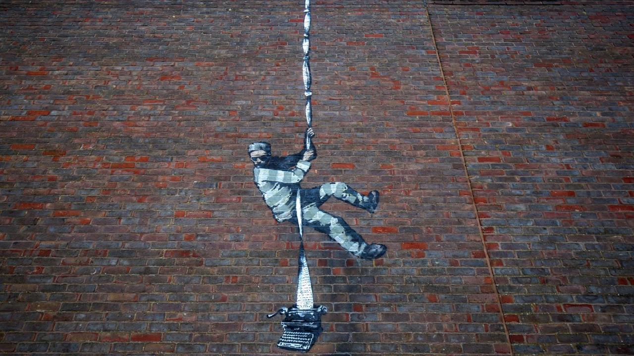 Das Kunstwerk an einer Außenmauer zeigt einen ausbrechenden Häftling. Das Kunstwerk an einer Außenmauer zeigt einen ausbrechenden Häftling.