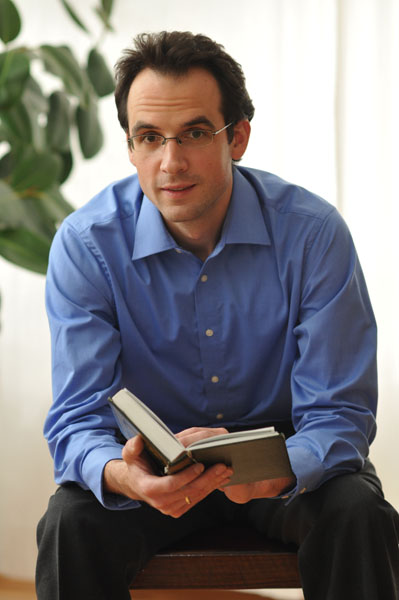 Nicolai Sinai mit einem aufgeschlagenen Buch.