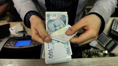 Ein Angestellter in einer Wechselstube zählt türkische Lira-Scheine. Die Währung ist im Juni 2015 um mehr als sechs Prozent gefallen. AFP PHOTO / OZAN KOSE / AFP PHOTO / OZAN KOSE