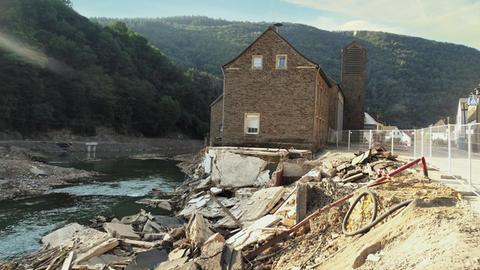 Ein Haus steht an der Ahr inmitten von Trümmern