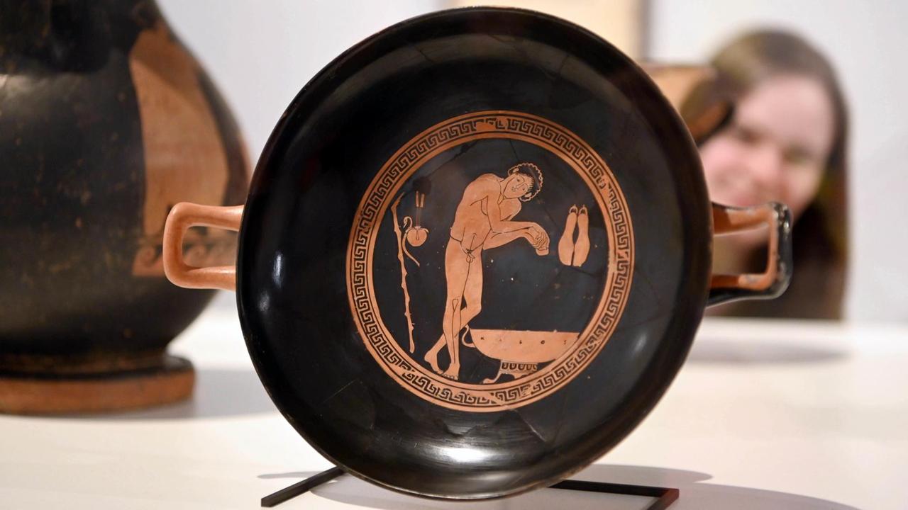 Rrotfigurige Schale, dem athenischer Vasenmaler Onesimos zugeschrieben, aus dem 5. Jahrhundert vor Christus. Drauf ist eine Waschznesze mit einem Mann zu sehen, umringt von einem Mäander Ornament.