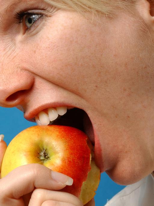 Eien Frau beißt in einen Apfel.