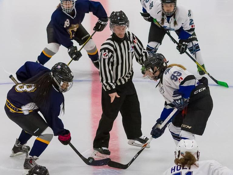 Zwei Eishockey-Frauenteams stehen sich zu einem Face-off gegenüber.
