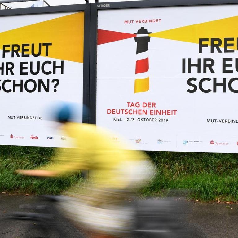 Ein Radfahrer fährt an Plakaten mit der Aufschrift "Freut Ihr Euch schon" entlang. 