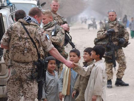 Bundeswehrsoldaten des ersten deutschen Einsatzkontingentes der ISAF in Kundus, Afghanistan, begrüßen am 16. Feb. 2004 afghanische Kinder auf einer Strasse in Taloqan