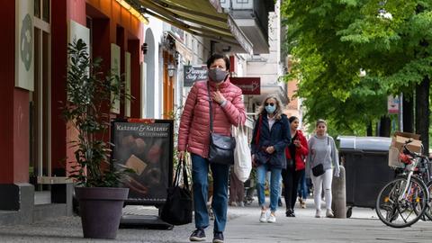 Frau mit Gesichtsmaske läuft auf Gehweg