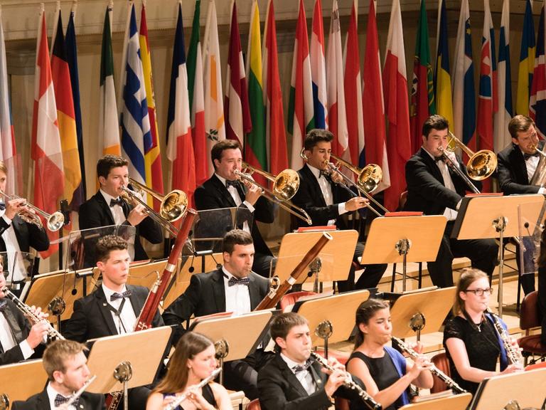 Hinter den Musikern des Orchester sind viele Fahnen der EU-Länder aufgestellt.