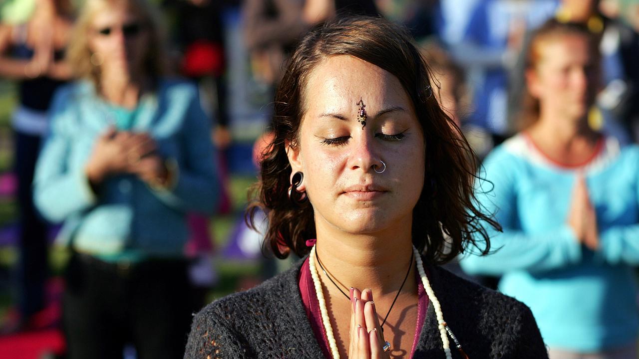 Eine Frau steht in Berlin beim Yogafestival in der Danksagungshaltung "Namaste".