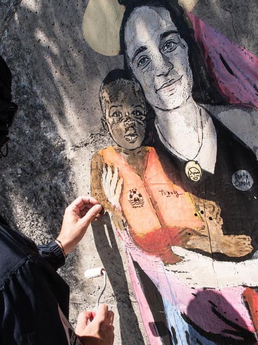 Der Street-Artist TVBOY malt sein Graffiti von Carola Rackete als Marienfigur an eine Wand in der sizilianischen Hafenstadt Taormina.