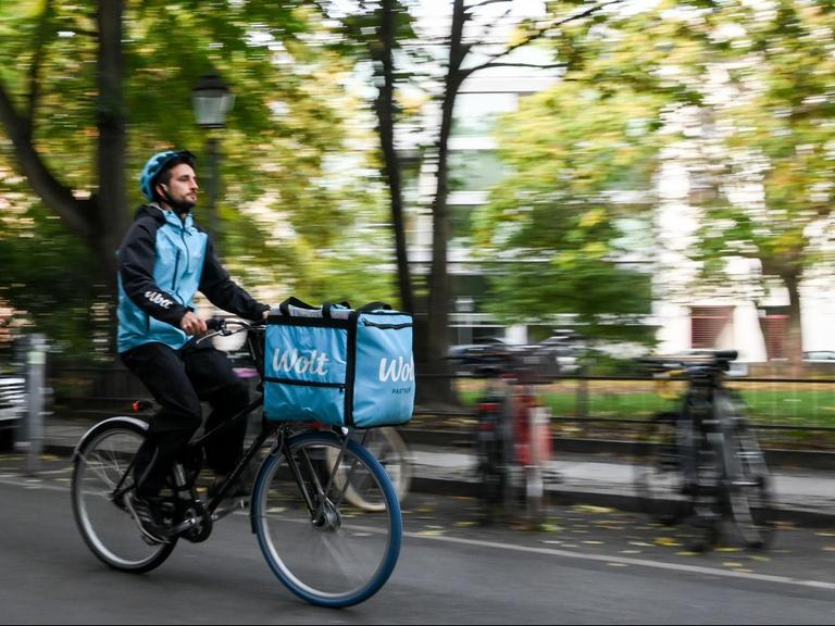 Ein Fahrradkurier ist für den Essenslieferdienst Wolt in einer Straße in Berlin-Mitte unterwegs.