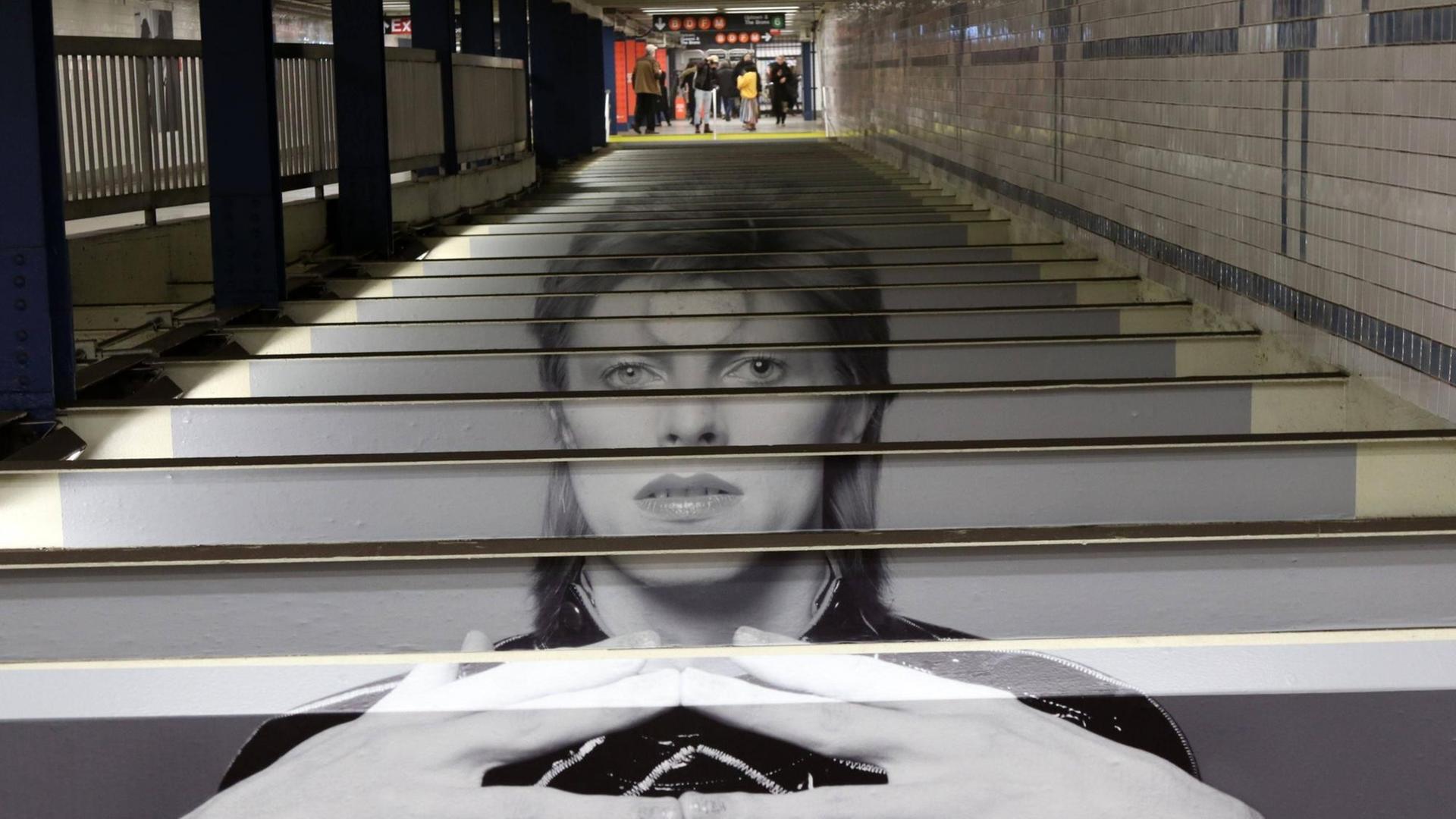 Über die Treppenstufen in der New Yorker U-Bahn ist ein Abbild von David Bowie gedruckt.